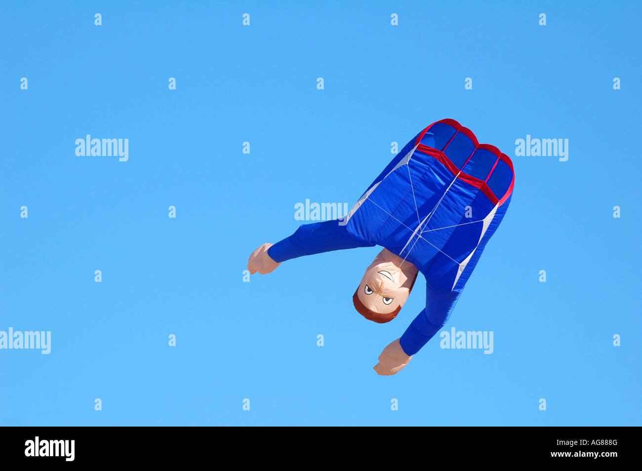 a kite of the upper body of a male flying upside down against a blue