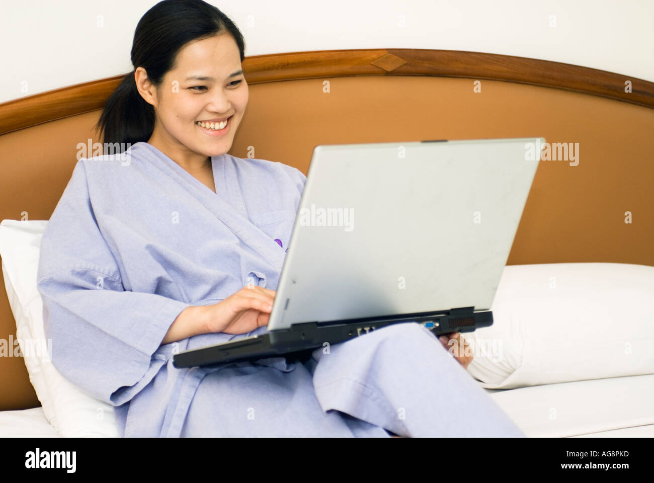 Chinese Young Woman Laying On Bed In Hotel Room Working On Laptop Computer Bangkok Thailand Stock Photo
