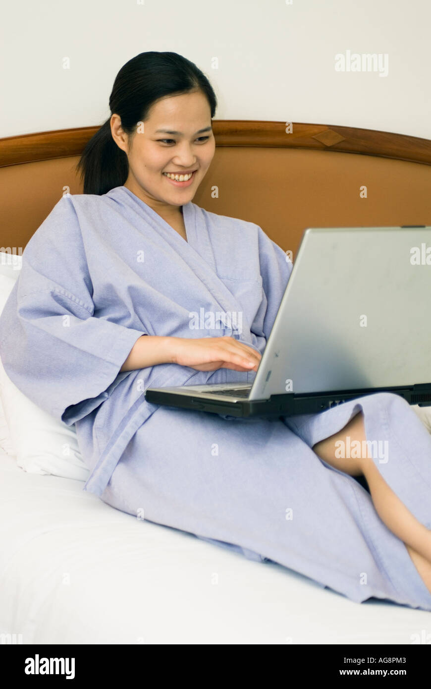 Chinese Young Woman Laying On Bed In Hotel Room Working On Laptop Computer Bangkok Thailand Stock Photo