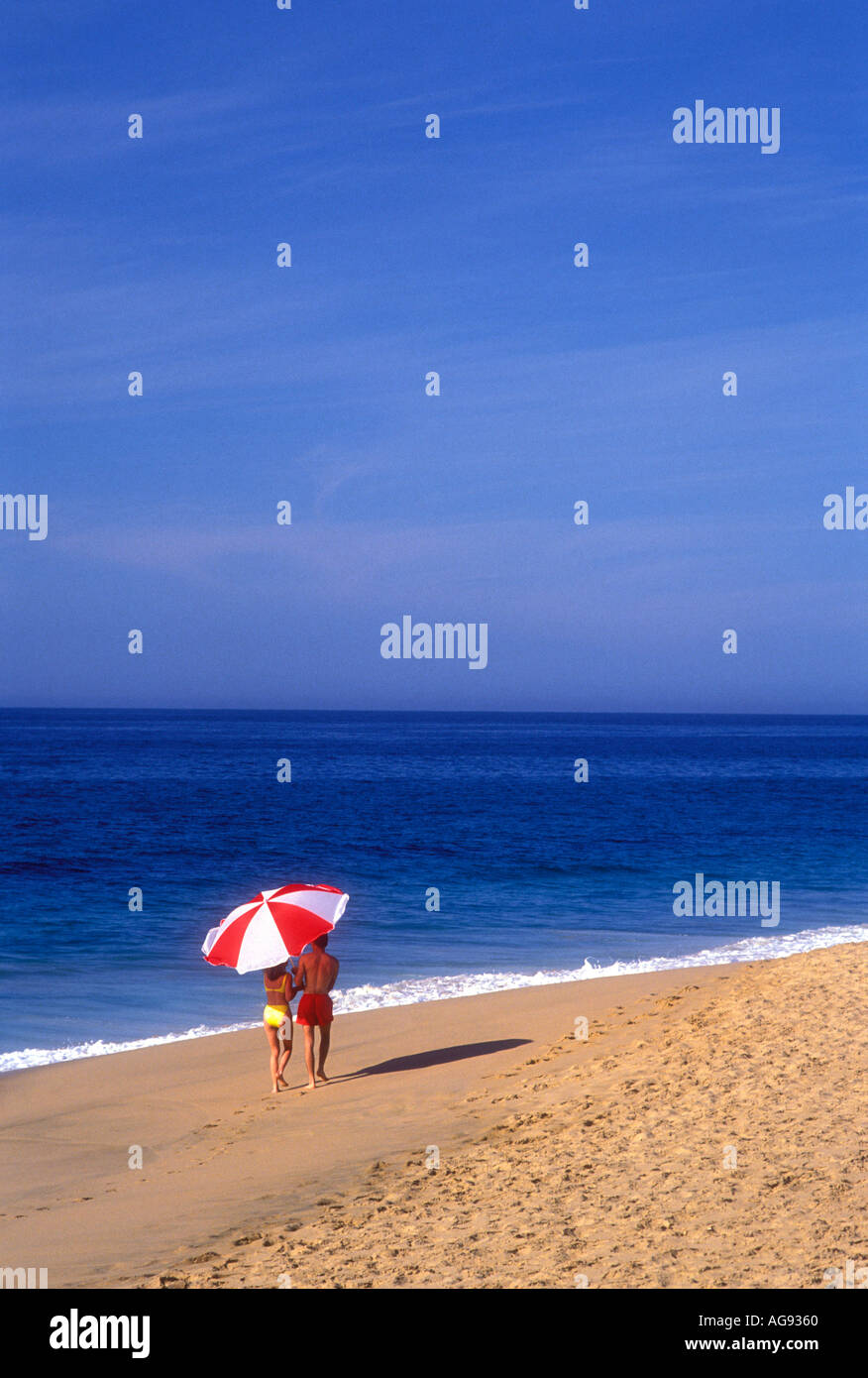 Couple walking on beach under large umbrella in Cabo san Lucas Mexico Model released image Stock Photo