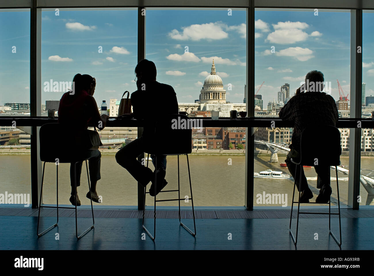 Silhouetted shapes of a visitor seated at a window overlooking the London skyline England. Stock Photo