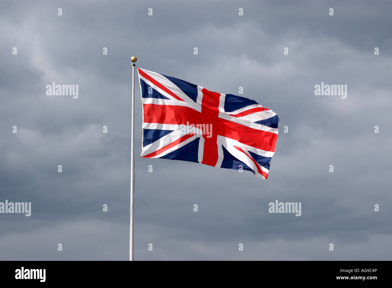 Union flag flying against a dark cloudy sky at Littlehampton UK Stock ...