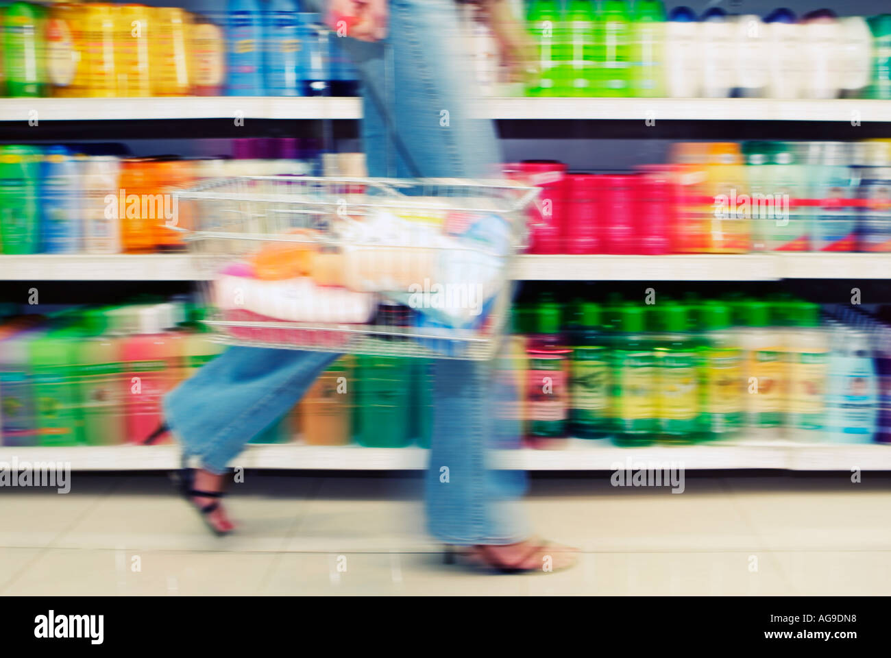 Young Woman Carrying a Shopping Basket in the Aisle of a Supermarket Low Section Stock Photo
