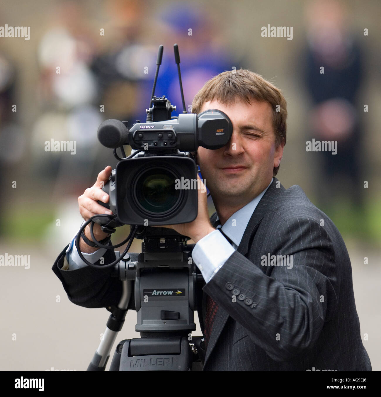 Cameraman wearing a suit looking through the viewfinder at outdoors event  Stock Photo - Alamy