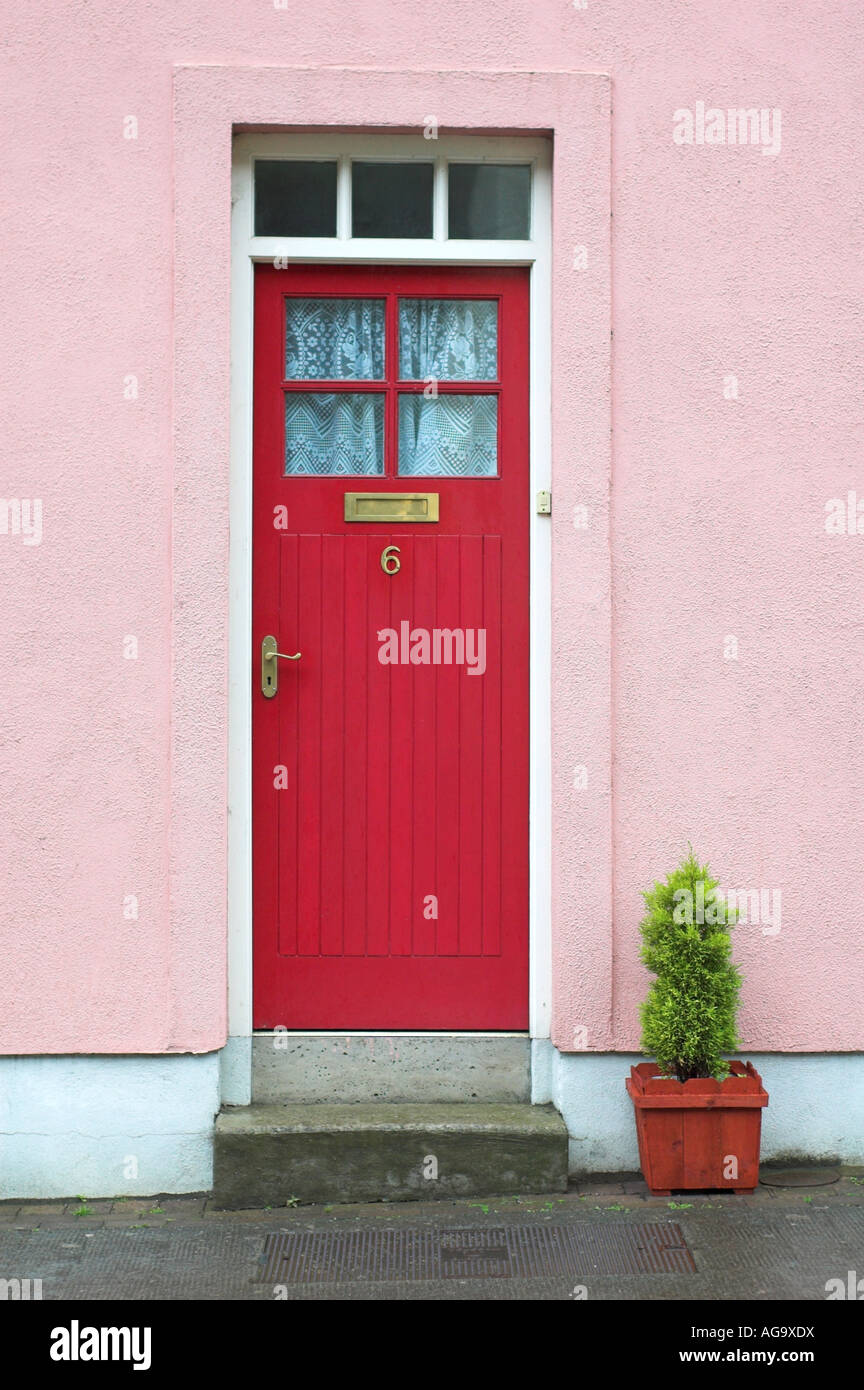 A red door on a pink cottage in Avoca Village, County Wicklow Ireland Stock Photo