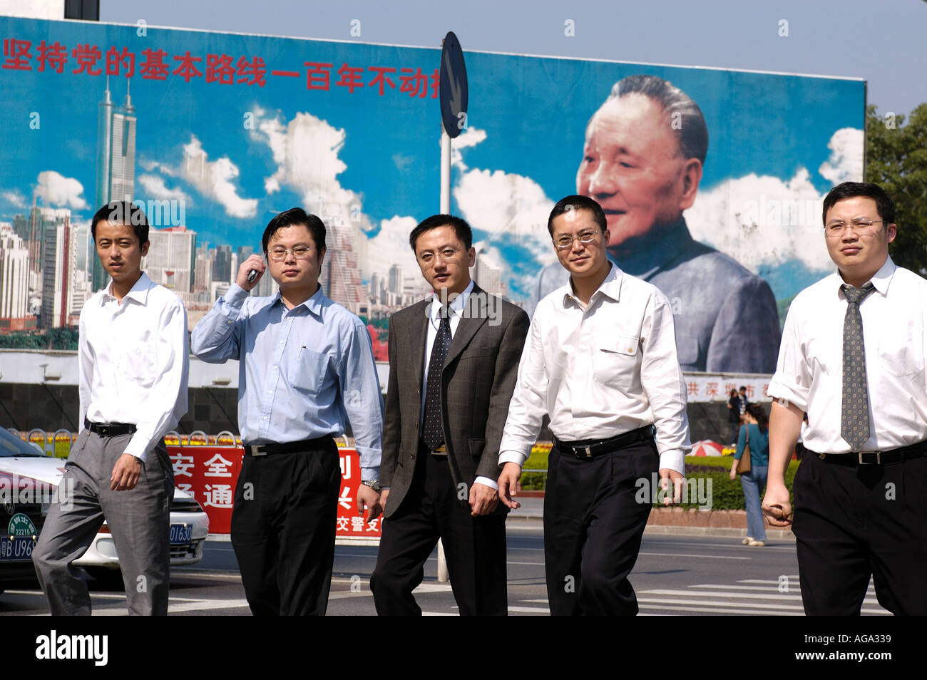 Office workers walk in front of a mural of Deng Xiao Ping that commemorates the founding of Chinas first Special Economic Zone 2 Stock Photo
