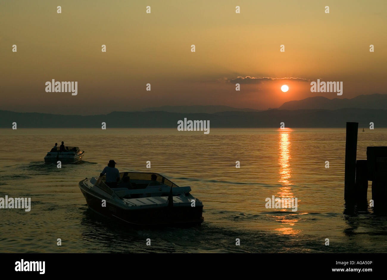 Power boats leave port on Lake Garda Italy at sunset 2007 Stock Photo
