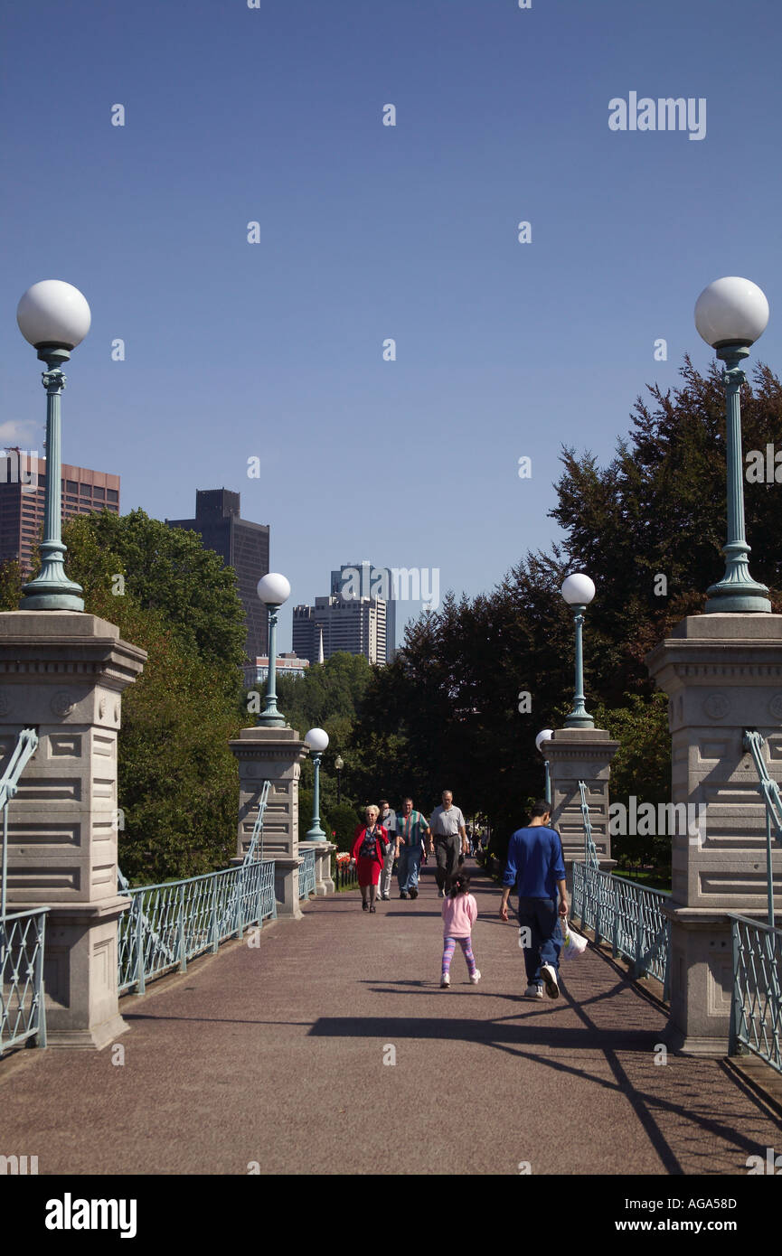 People walking over foot bridge at Boston Public Garden with city ...