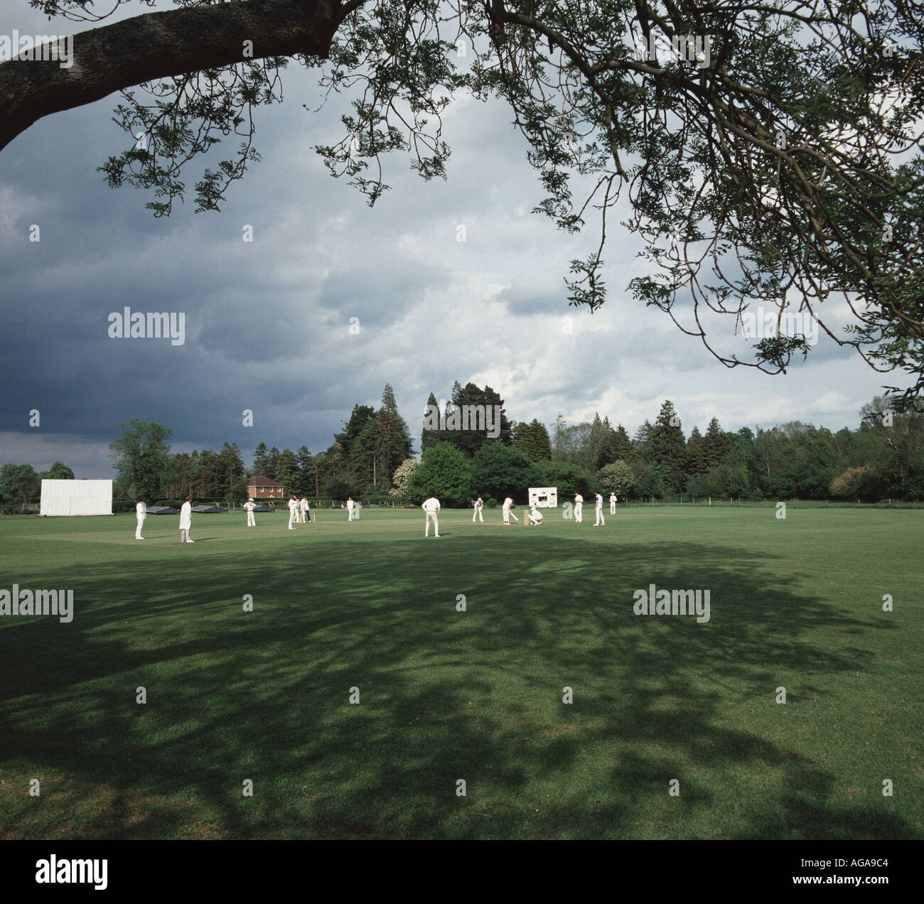 A cricket match held on the village green at Longparish Hampshire on a typical English summer day with sunshine and clouds Stock Photo