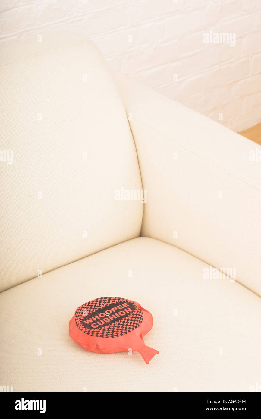 still life of red whoopee cushion on white arm chair Stock Photo