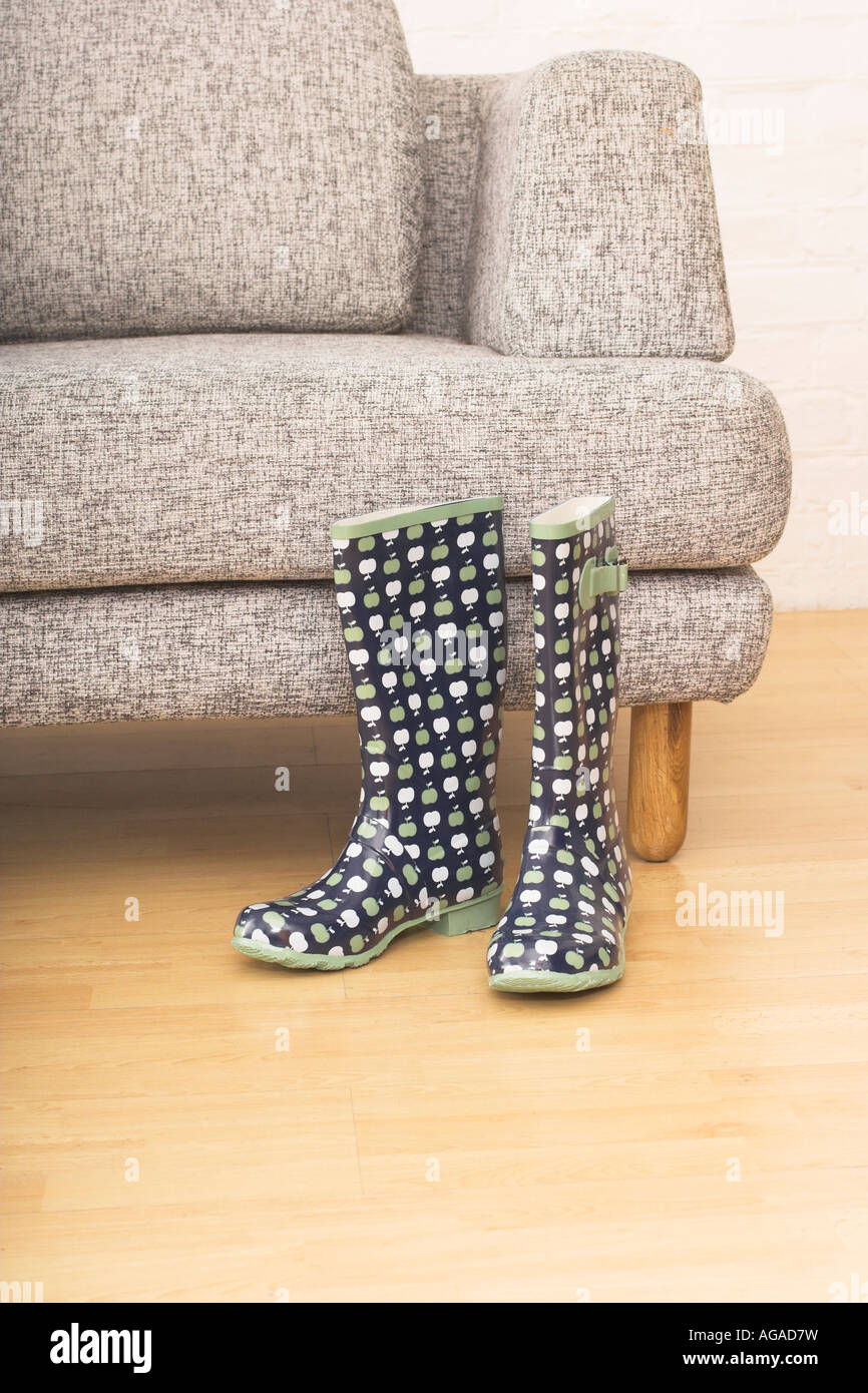 still life with pair of rubber boots in front of grey arm chair Stock