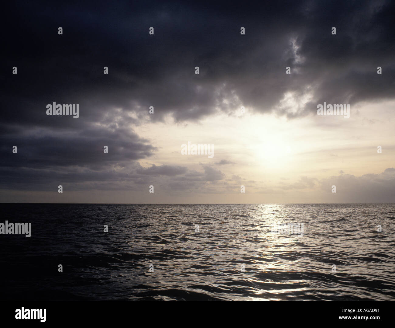 Sea scape with sun shining through hole in the clouds Stock Photo