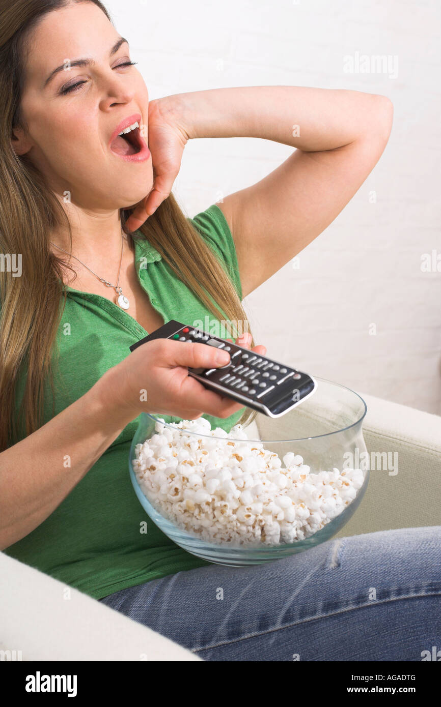young woman watching tv holding remote control and eating popcorn Stock ...
