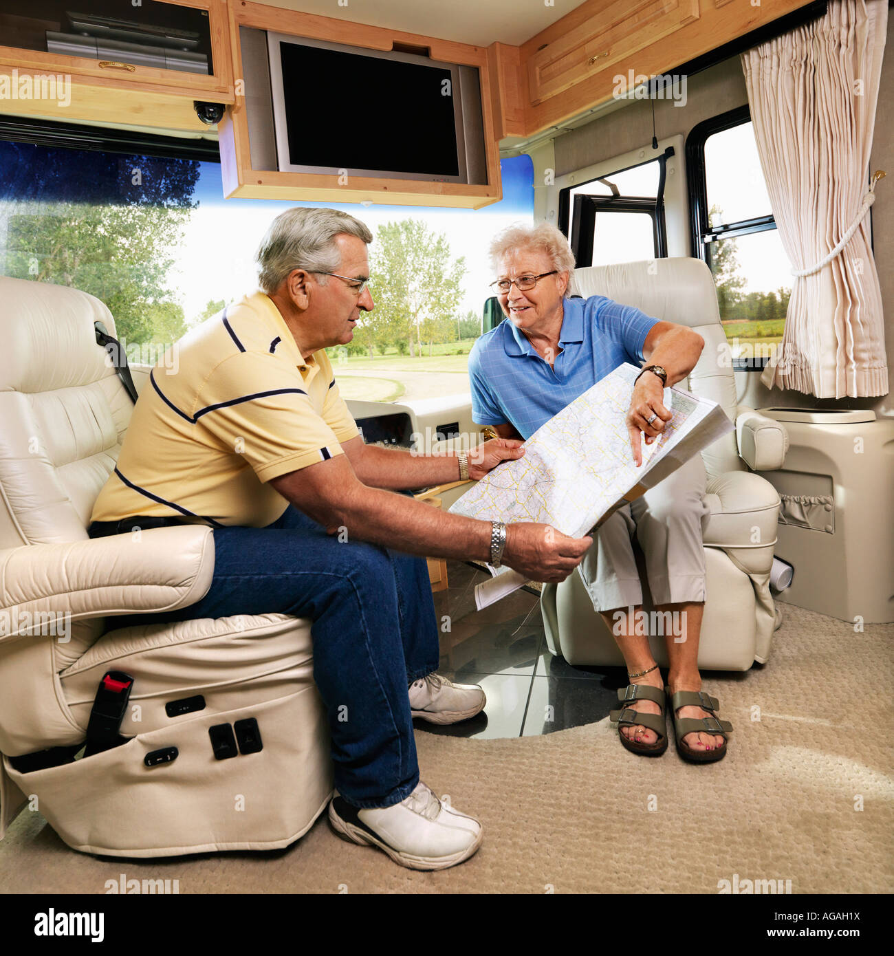 Senior couple sitting in RV looking at map and smiling Stock Photo