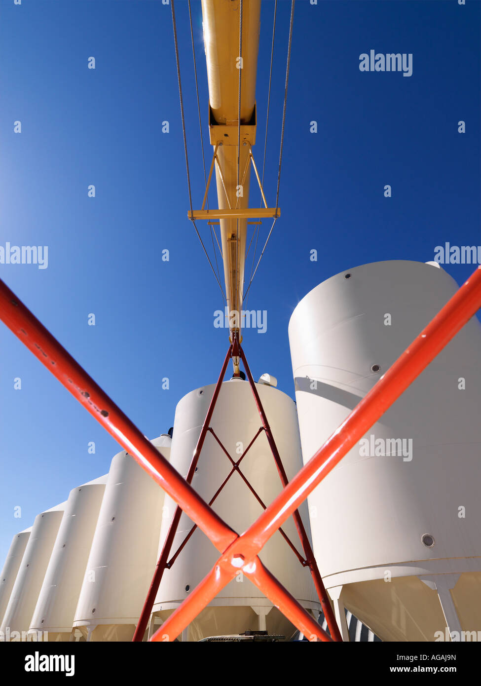 Low angle view of metal grain storage silo facility against blue background Stock Photo
