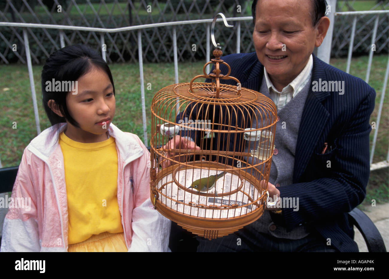 China, Hong Kong ,Grandfather and granddaughter with caged bird Stock Photo
