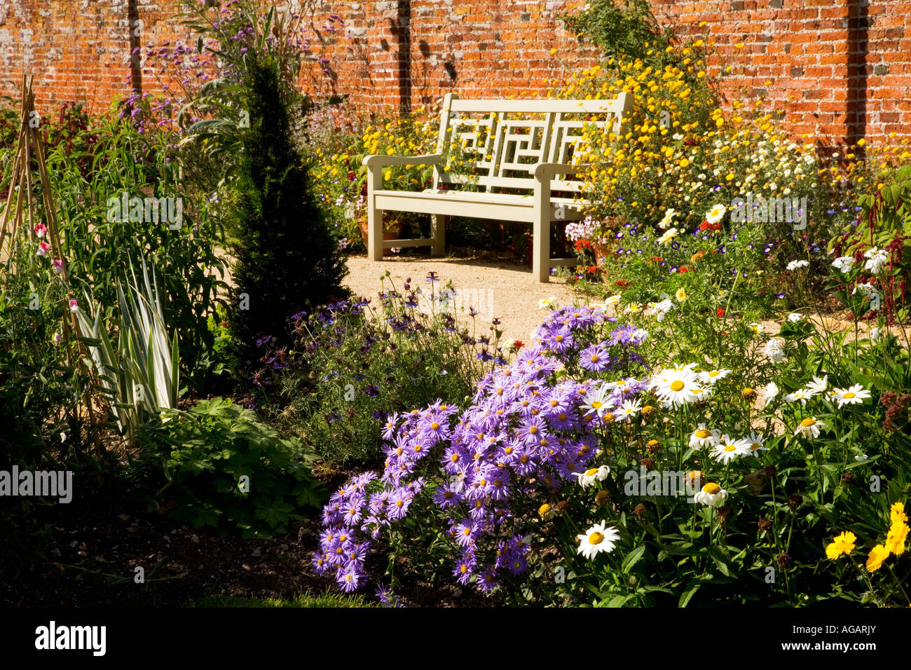 Garden seat, with purple dwarf asters and Shasta daisies, in the Walled Garden at Lydiard Park, Swindon, Wiltshire, England, UK Stock Photo