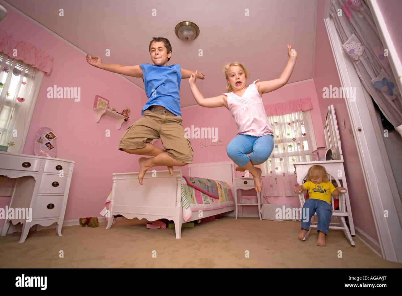 3 kids jumping at home in a pink bedroom, having fun Stock Photo Alamy