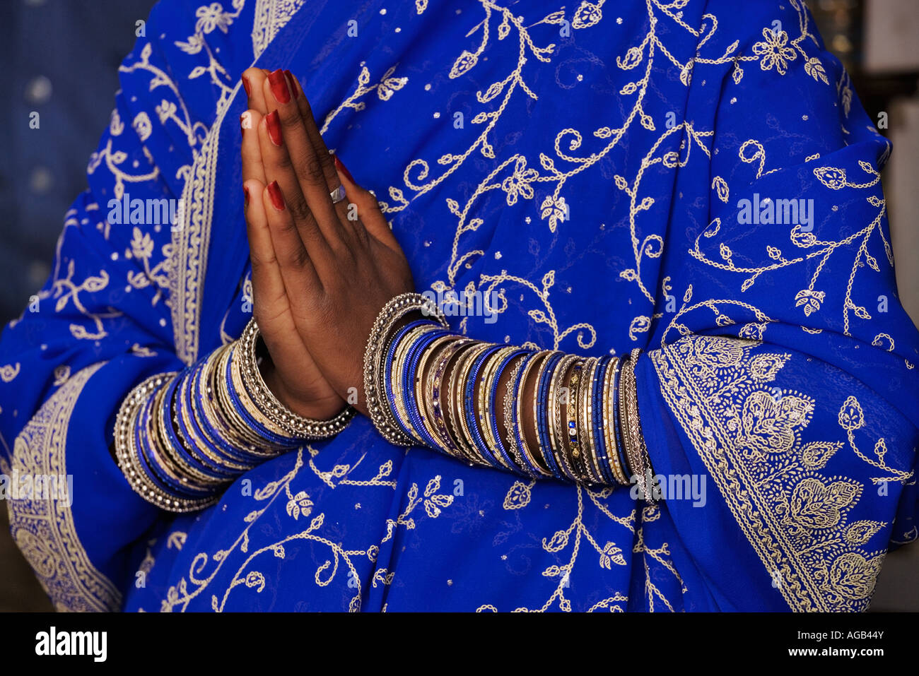 Indian woman in beautifully decorated sari with an assortment of bangles on her wrists She is performing the Namaskar gesture Stock Photo