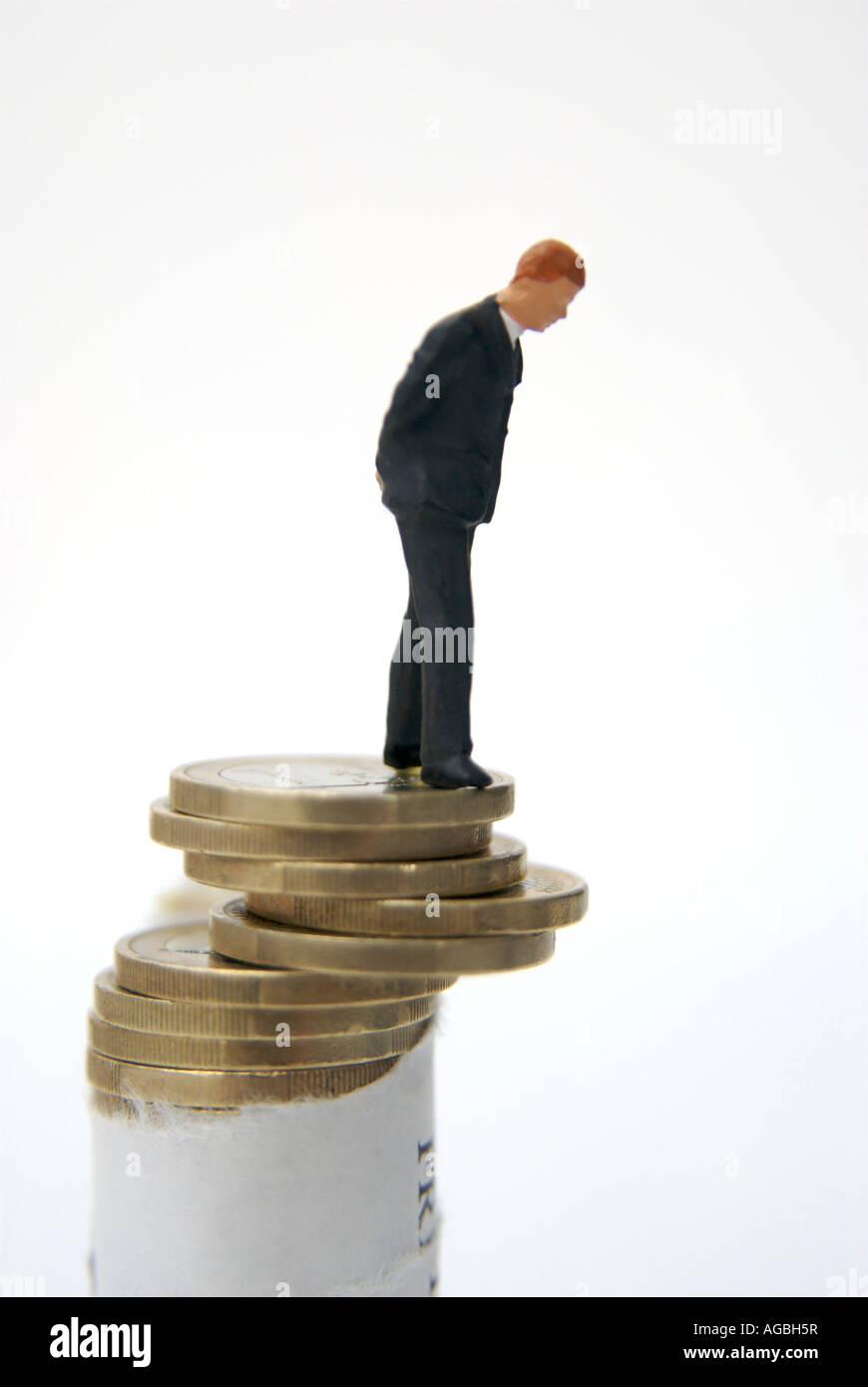 Businessman looking over the edge of a pile of euro coins - EU financial crisis / economic collapse / instability concept Stock Photo