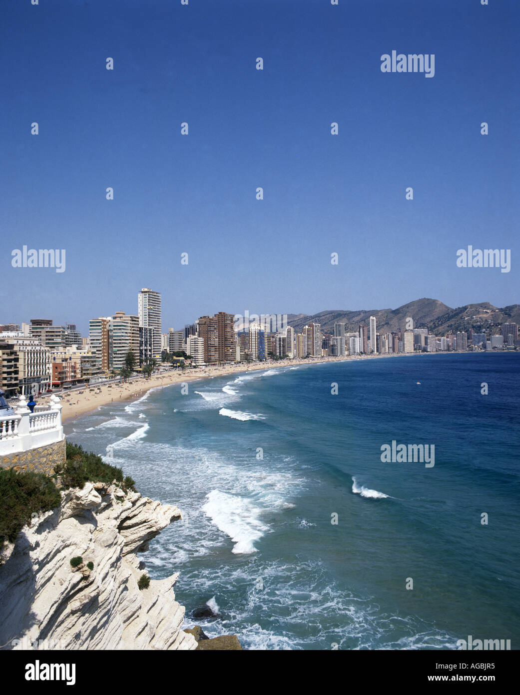 Long breakers rolling onto the beach almost completely fringed by massed skyscrapers at the resort of Benidorm Stock Photo