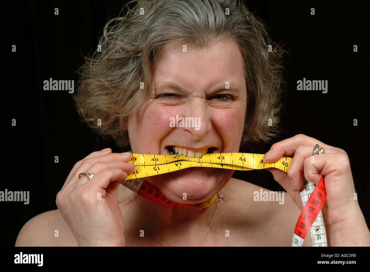 Elderly Woman chews tape measure Overweight Couch potato Stock Photo