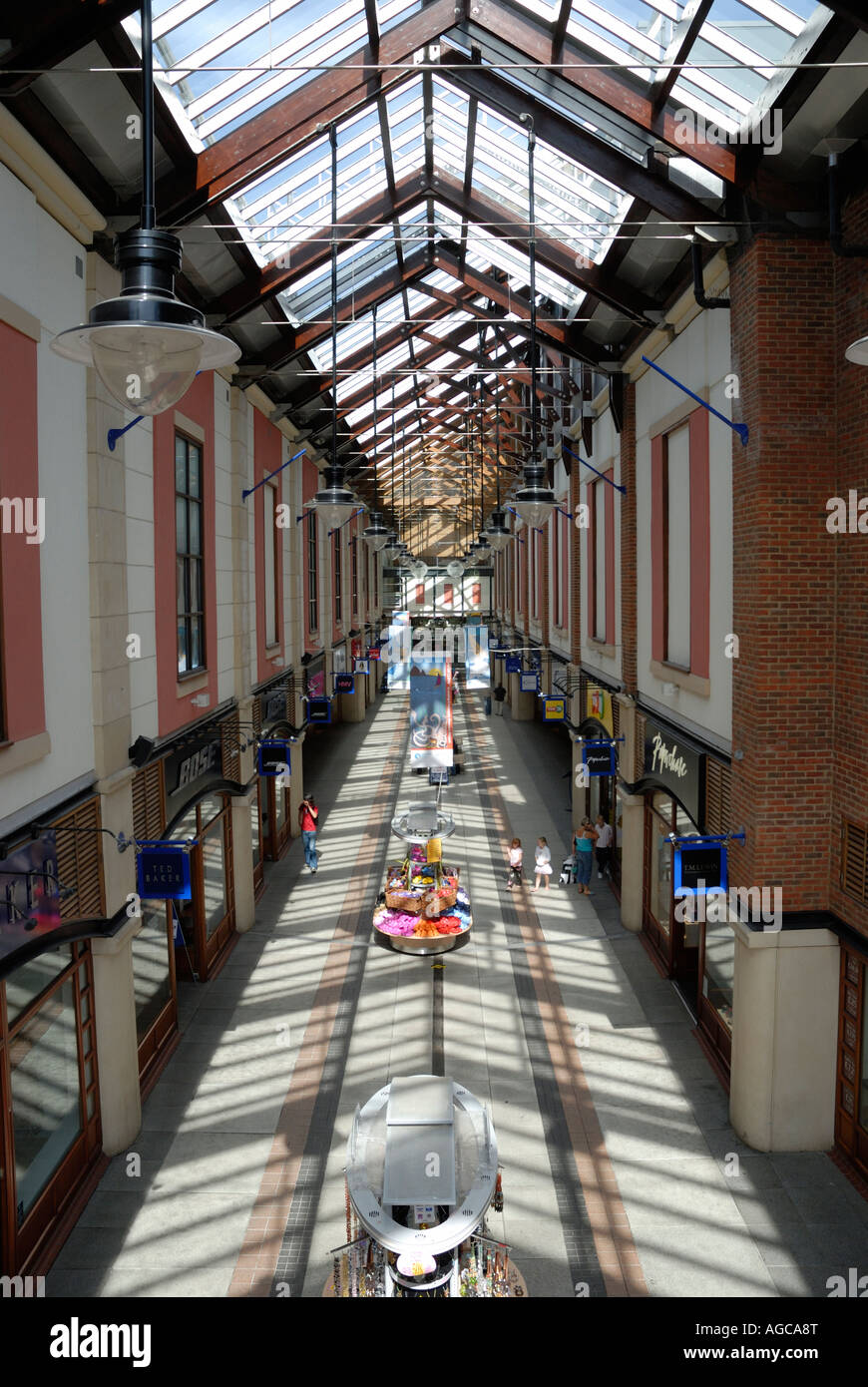 Enclosed shopping arcade with glazed roof, blue sky, sunlight and