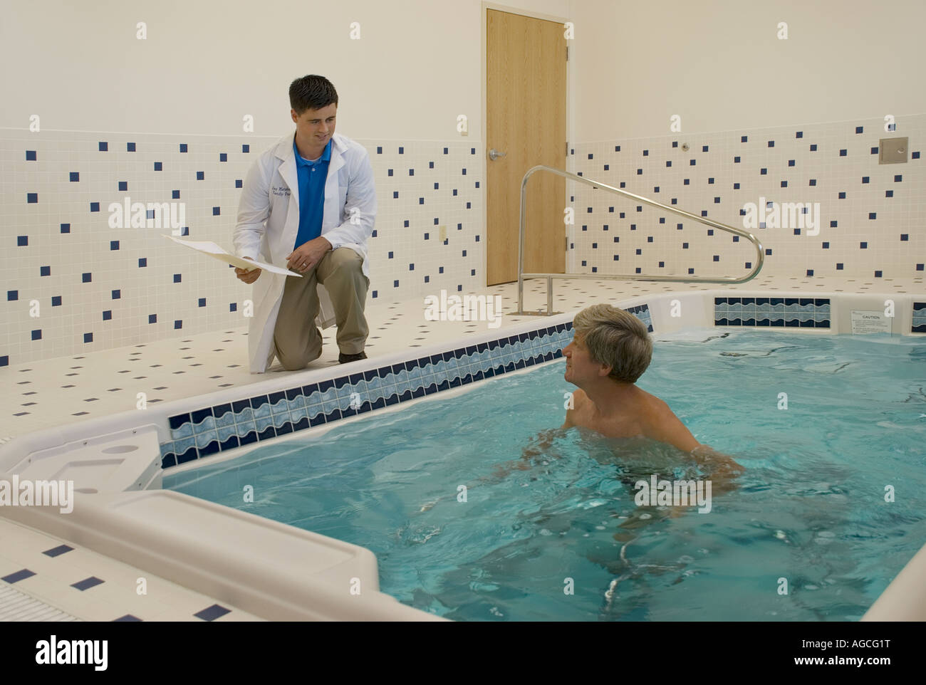 Physical therapist in lab coat monitoring middle aged male patient in