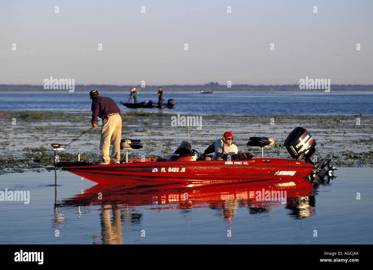 Anglers in red bass boat just after sunrise Stock Photo