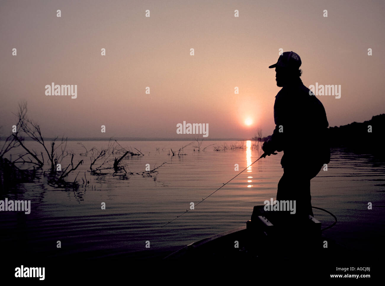 Fishing angling sunrise sunset fisherman silhouette holding rod Stock Photo