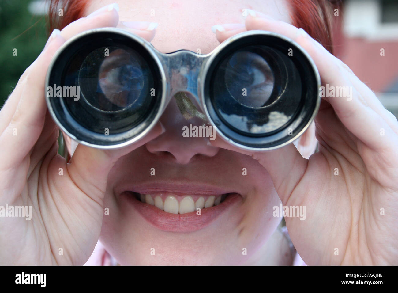 Teenaged girl smiling and looking through binnoculars, making her eyes