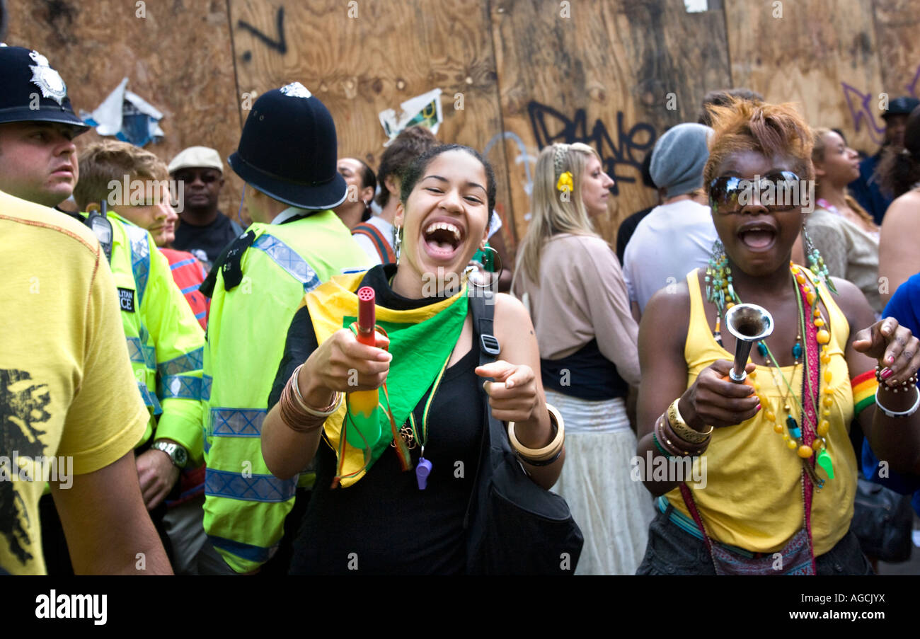 Two sassy, fashionable young black girls having fun at the Notting Hill Carnival 2007 while policemen look on. Stock Photo