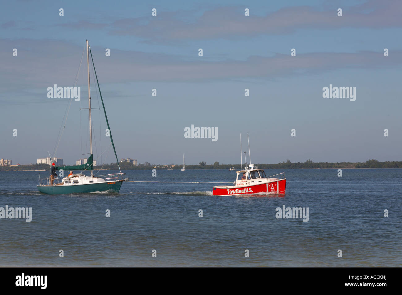 Tow boat pulling in crippled sailboat from Gulf of Mexico in southwwestern Florida near Fort Myers Beach Stock Photo