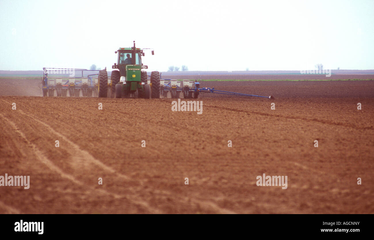 John Deere tractor planting a farm field in spring with soybeans Stock