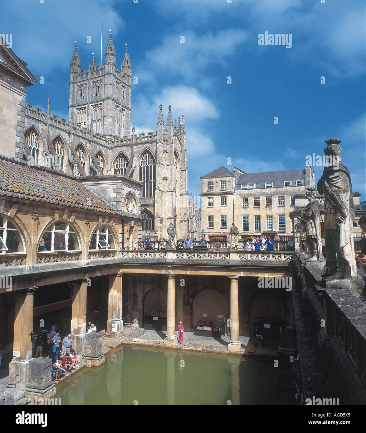 Statues stand on a ledge overlooking the green water of the hot springs of the Roman Baths which have existed at Bath for around 2000 years Bath Abbey in background Stock Photo