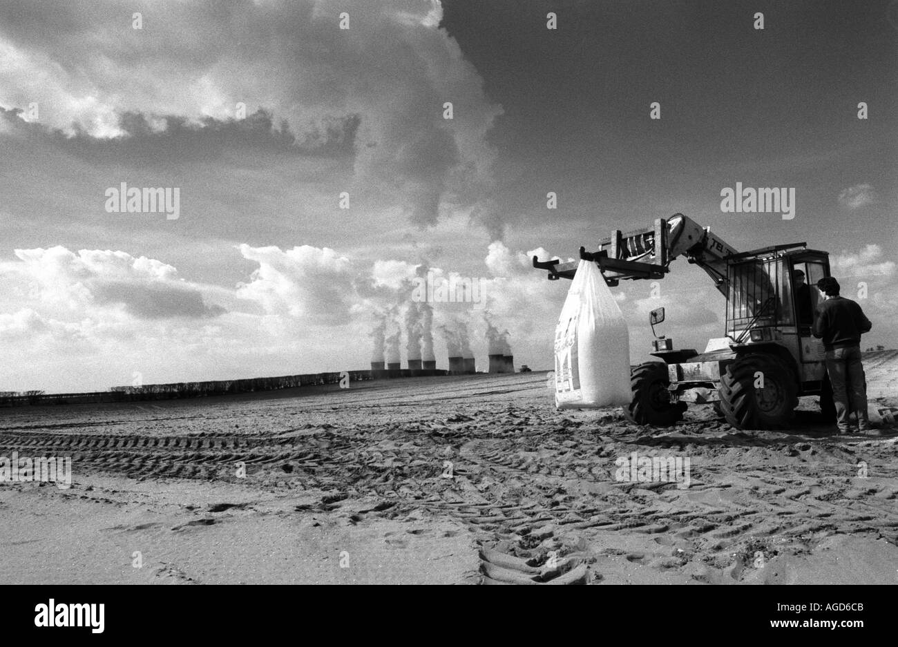 A tractor and farm workers in a field close to a power station in Lincolnshire, UK. Stock Photo