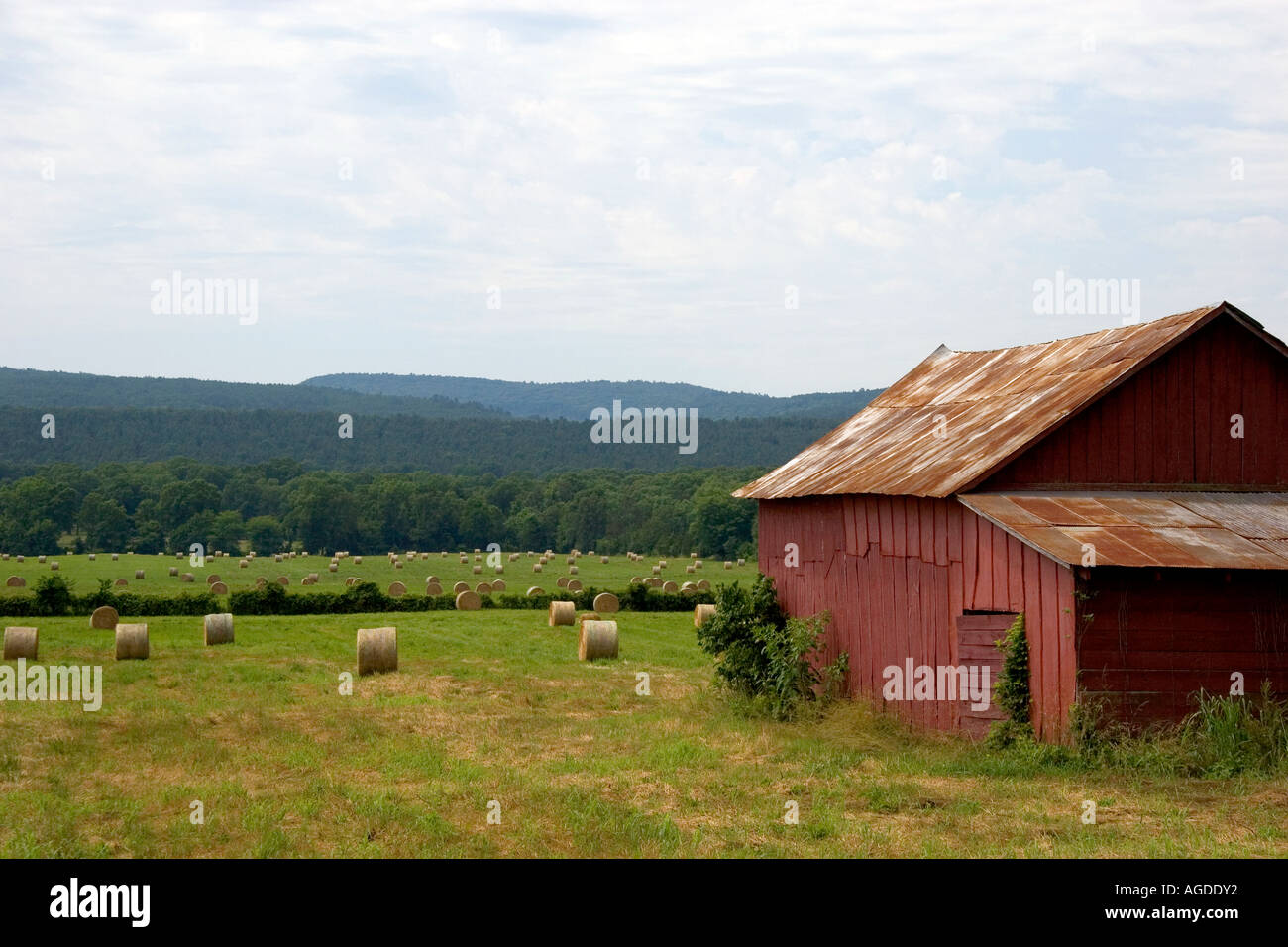 Round hay bales and red barn in northwest Arkansas. Stock Photo