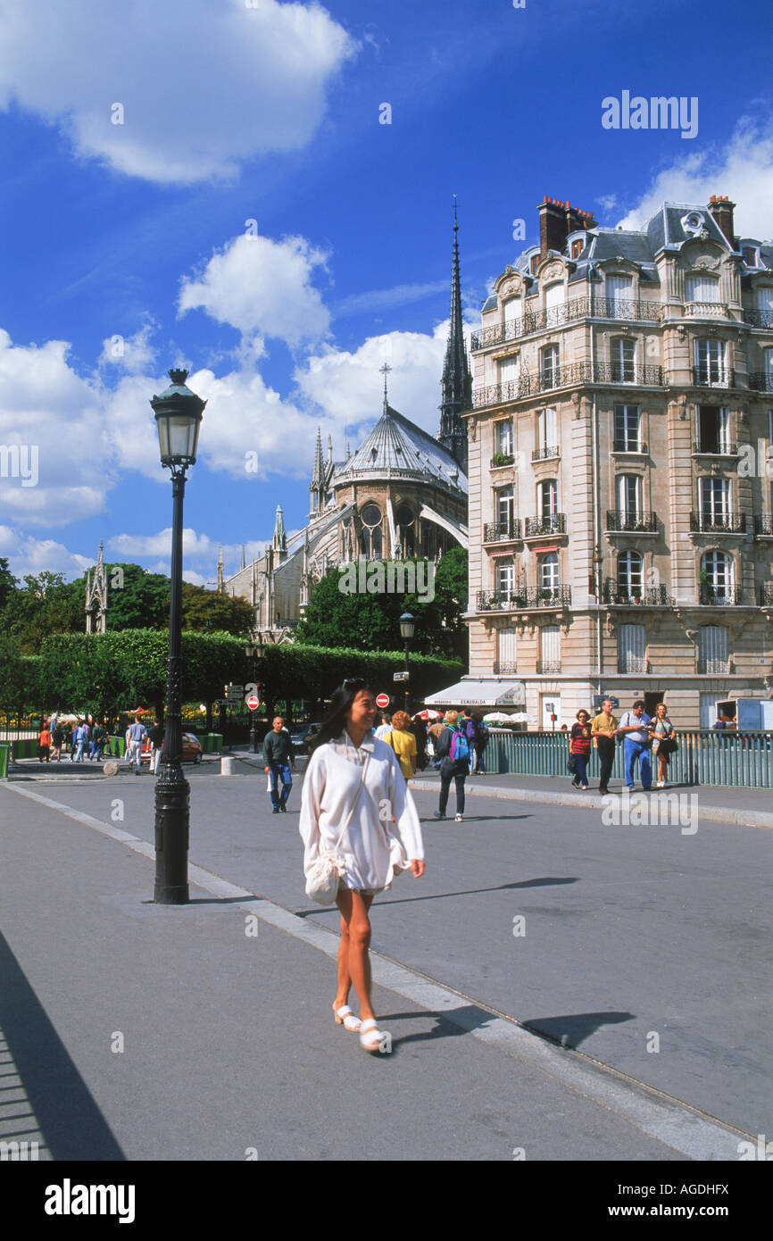 Female tourist crossing Pont Saint Louis with Notre Dame in Paris Stock Photo
