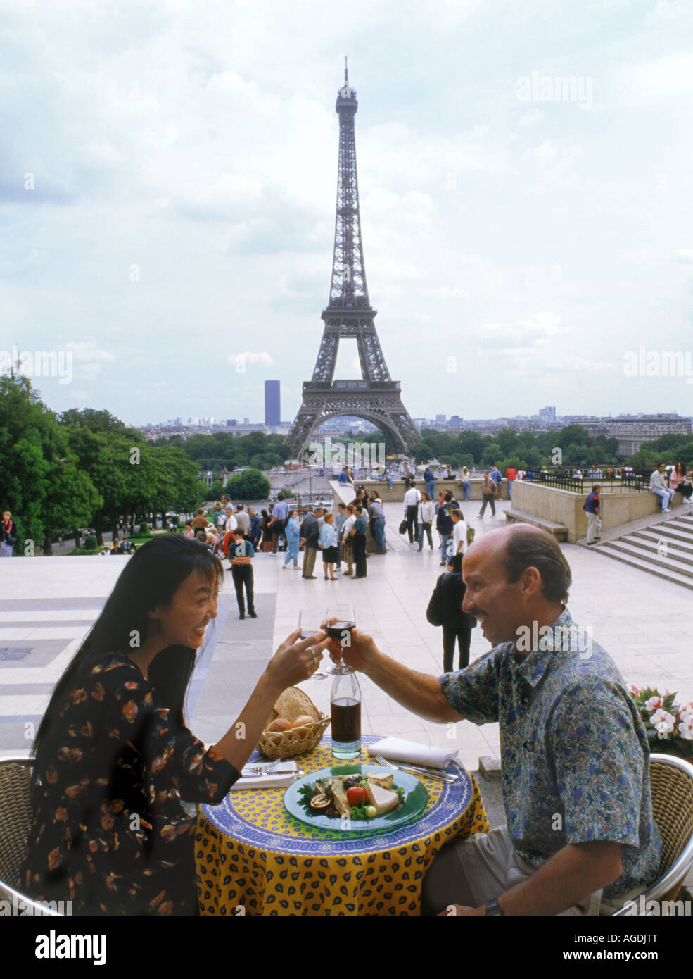 French wine, cheese, bread and tablecloth at Trocadero restaurant with Eiffel Tower and passing tourists Stock Photo