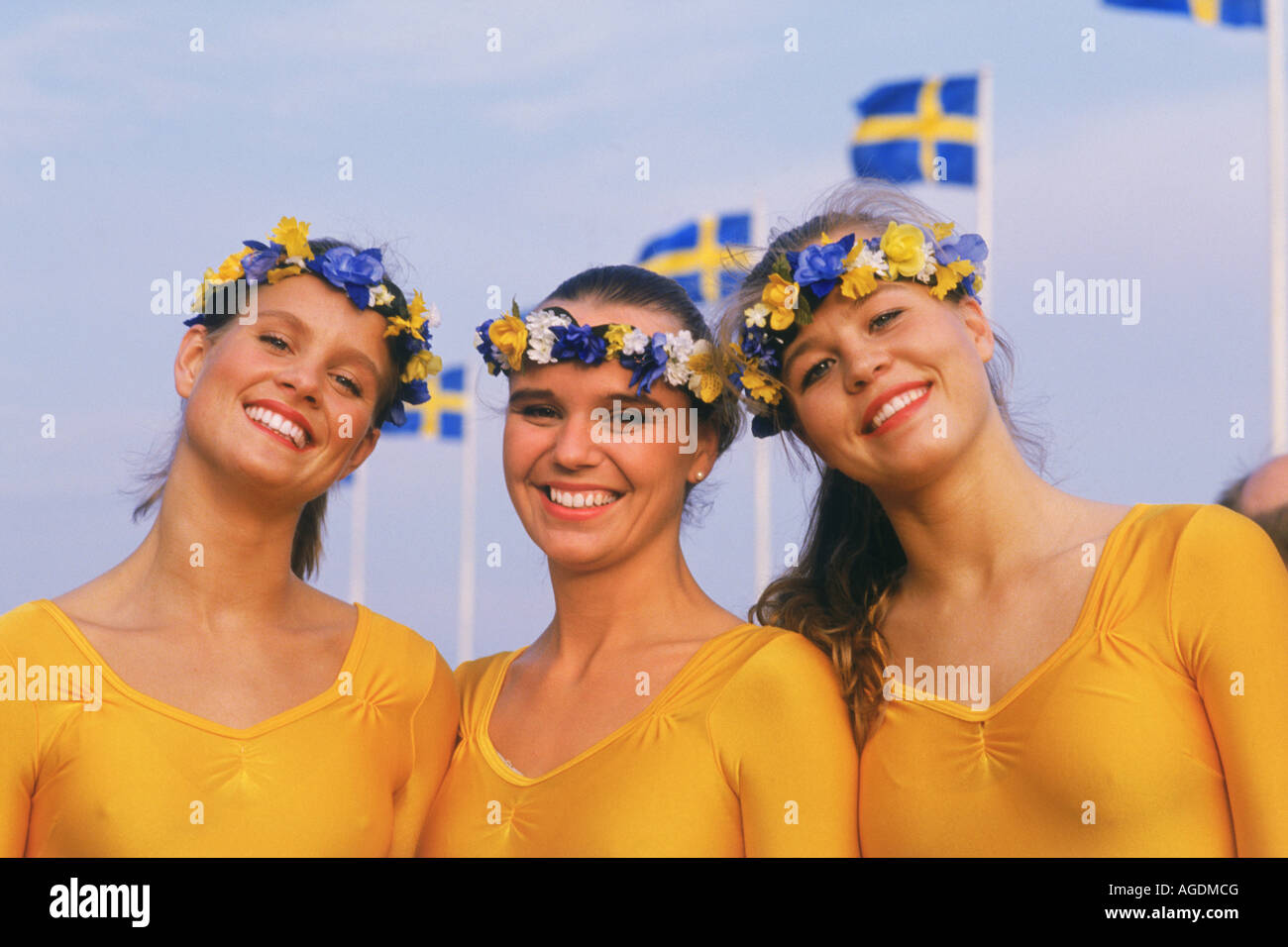 Three Swedish women with flower crowns and Swedish flags on Sweden's National Day June 6th Stock Photo