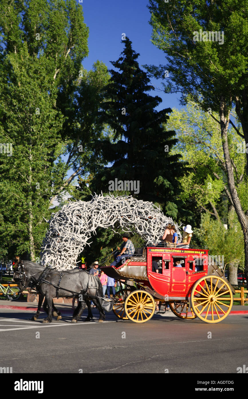 A stagecoach passes by the elk antler arch downtown Jackson Hole near Grand Teton National Park Wyoming Stock Photo