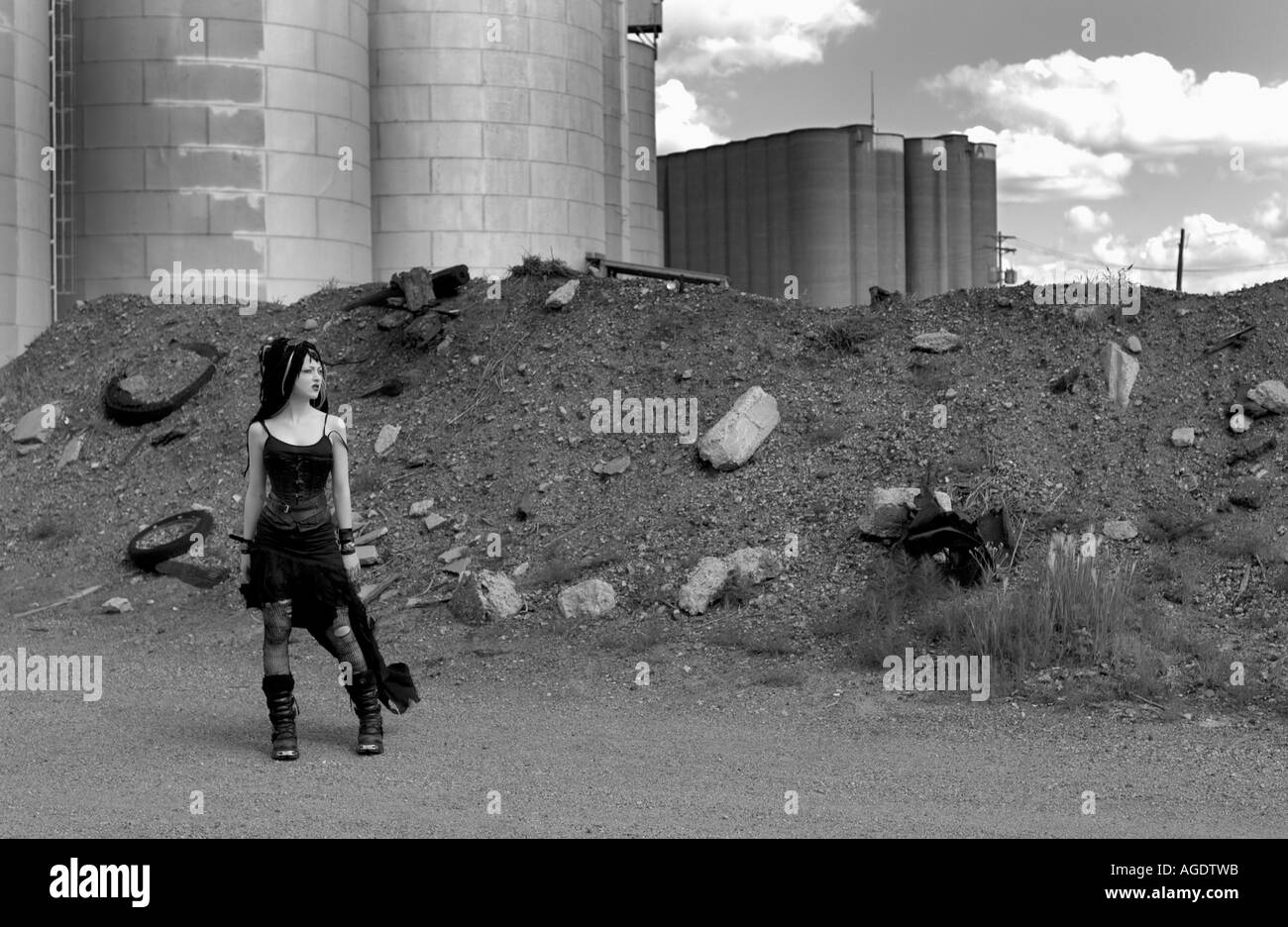 Goth girl standing in front of a pile of debris and silos Stock Photo