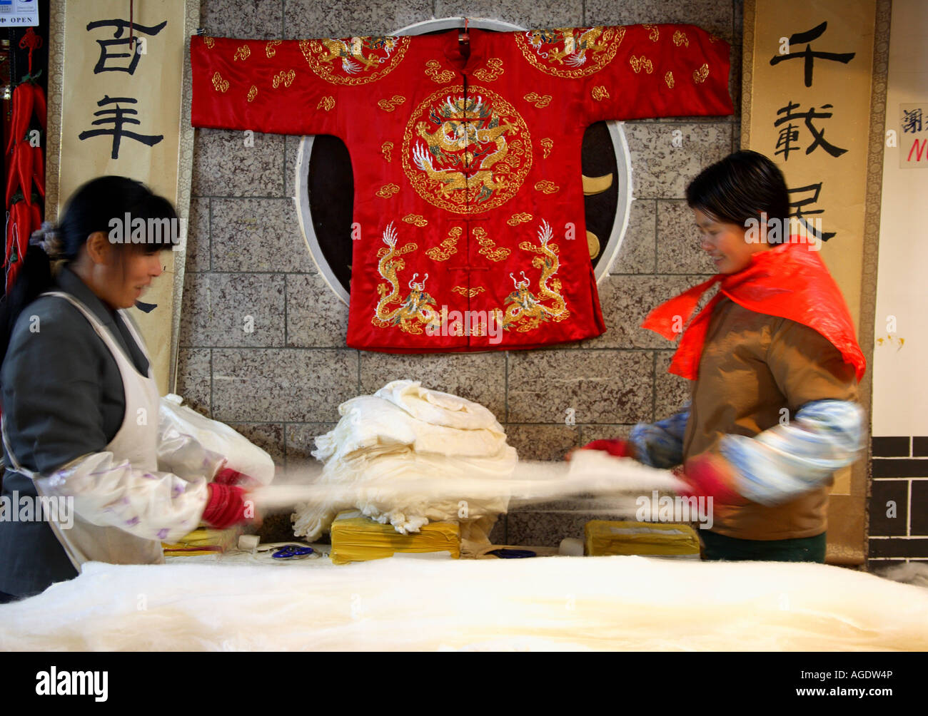 two Chinese women preparing silk sheets Stock Photo