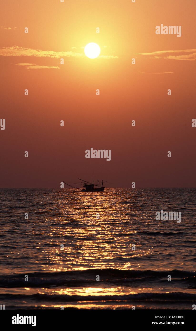Sun setting over sea at Koh Samet Thailand fishing boat silhouetted Stock Photo