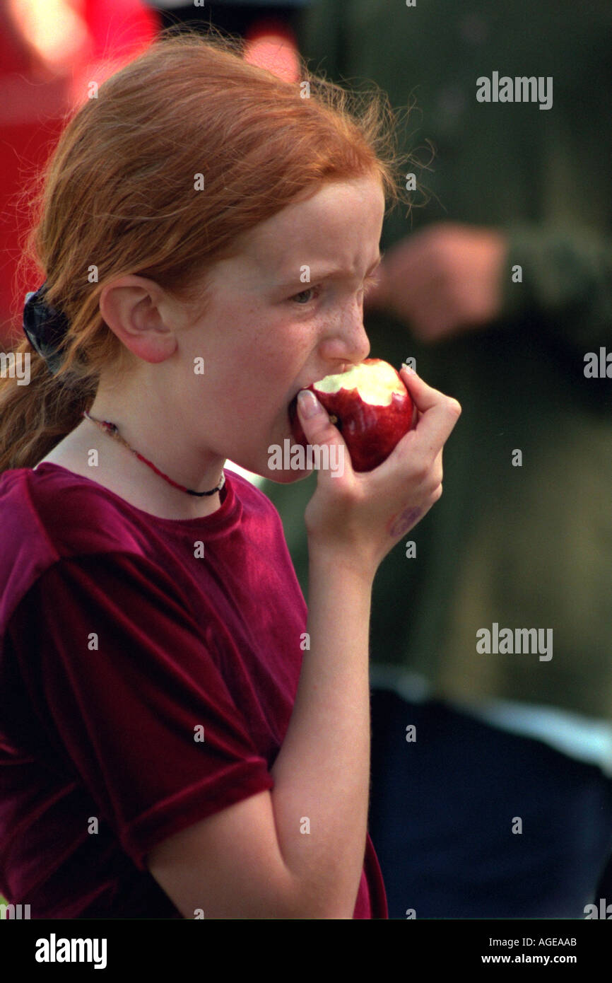 Girl age 12 eating a apple after the Catholic School Bike-A-Thon. St Paul Minnesota USA Stock Photo
