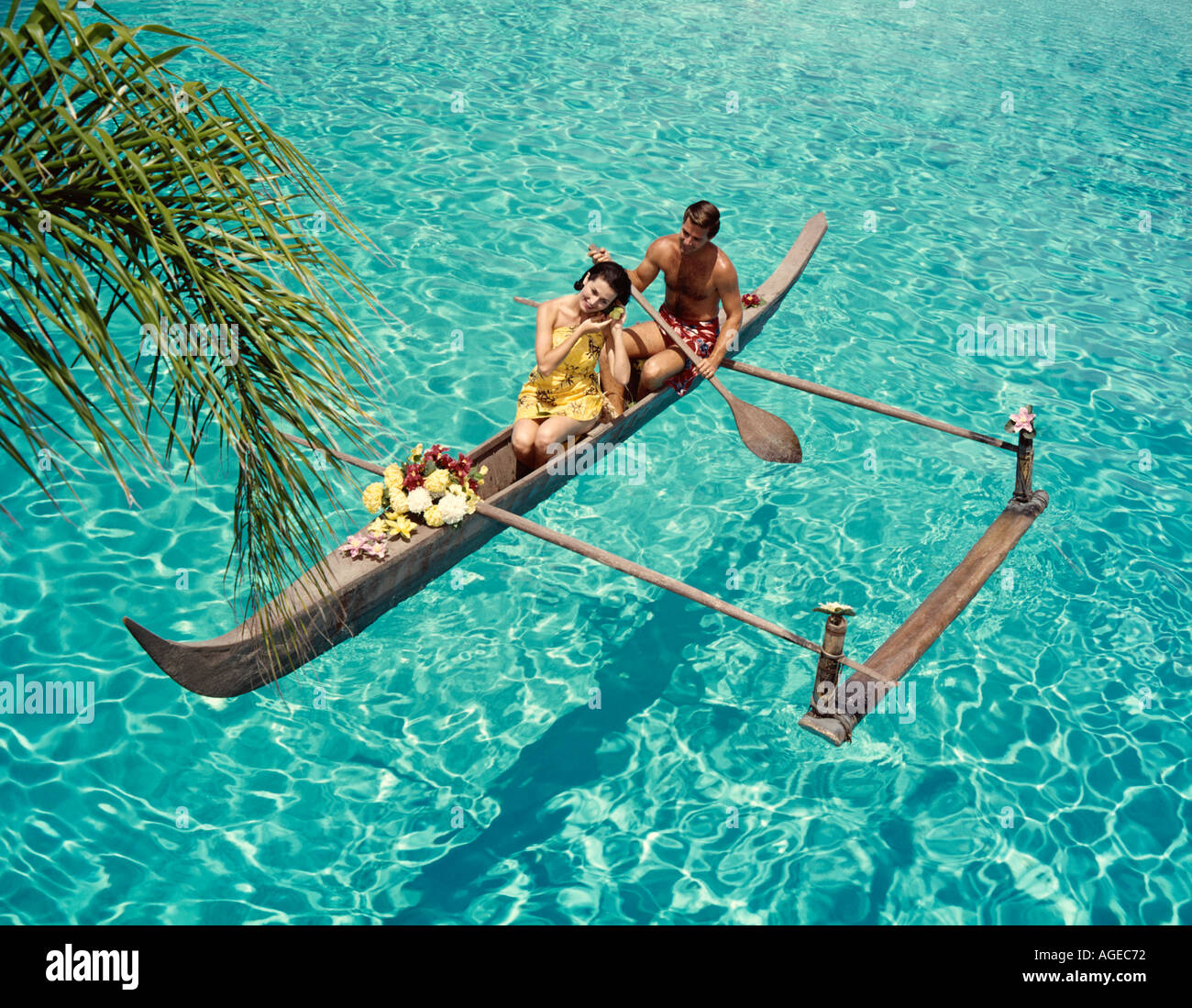 romantic couple in exotic outrigger canoe paddling in Caribbean Ocean Stock Photo