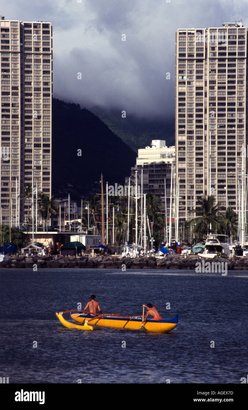 High school outrigger canoe team practising at the entrance to Ala Wai Canal with a storm building over the hills Stock Photo