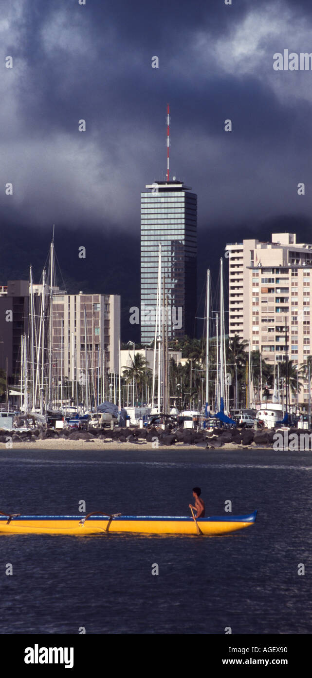 High school outrigger canoe team practising in Ala Wai Canal with a storm building over the hills Stock Photo