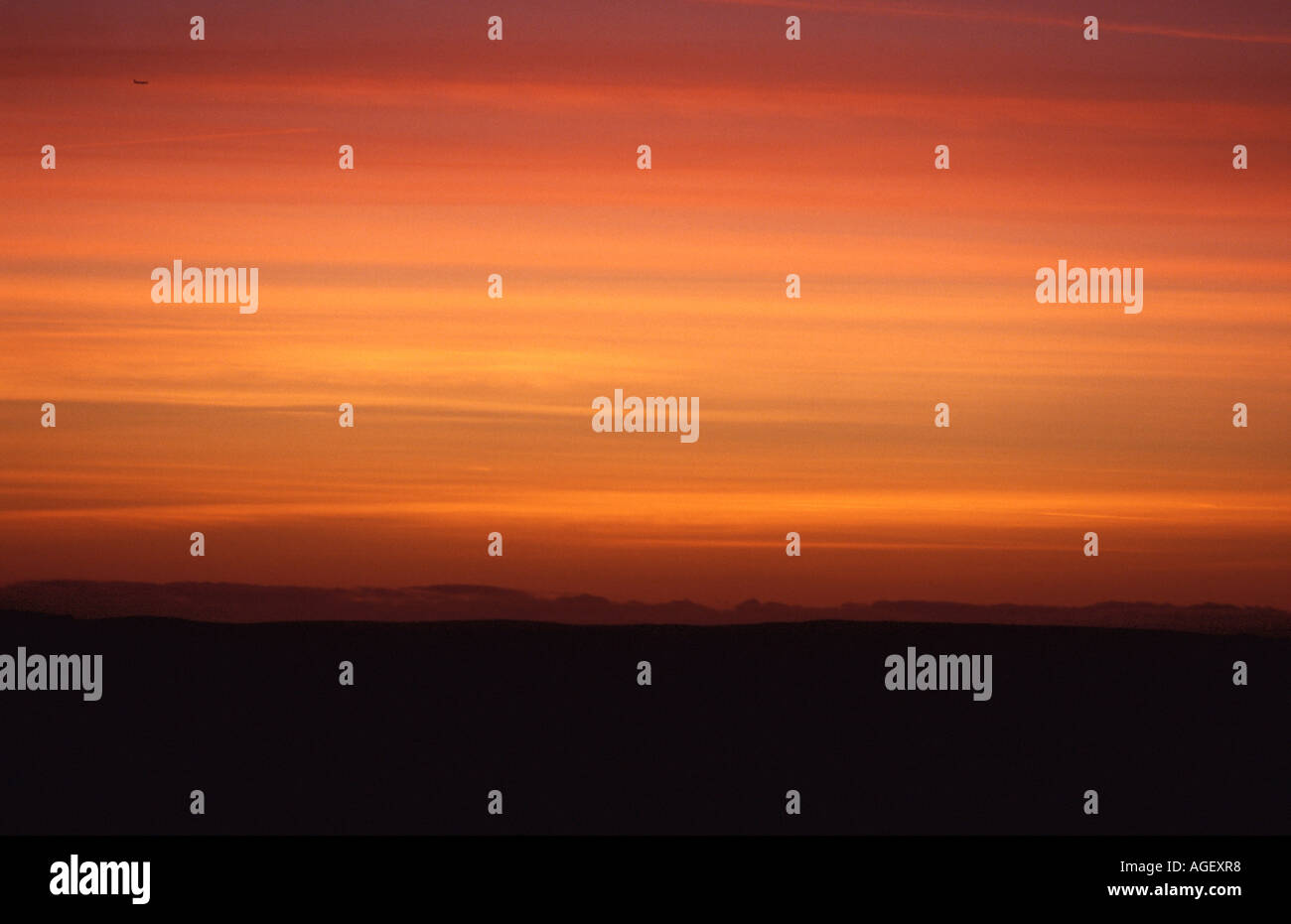 Sunset with jet plane dwarfed in a big sky in Peak District England