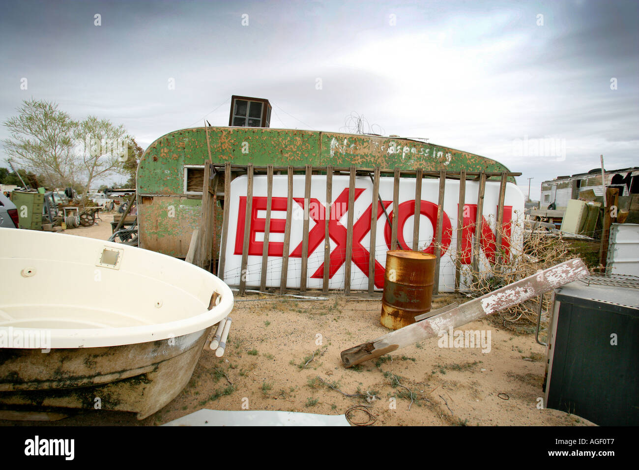 A junk yard in the Nevada Desert USA with scrap American cars and an old trailer big Exxon plastic sign Stock Photo